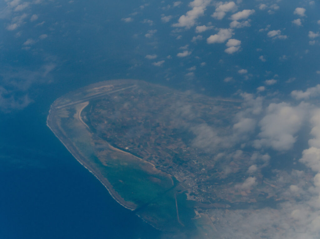 上空から望む久米島の南東海岸線、エメラルドグリーンの海とサンゴ礁に囲まれた離島の全景