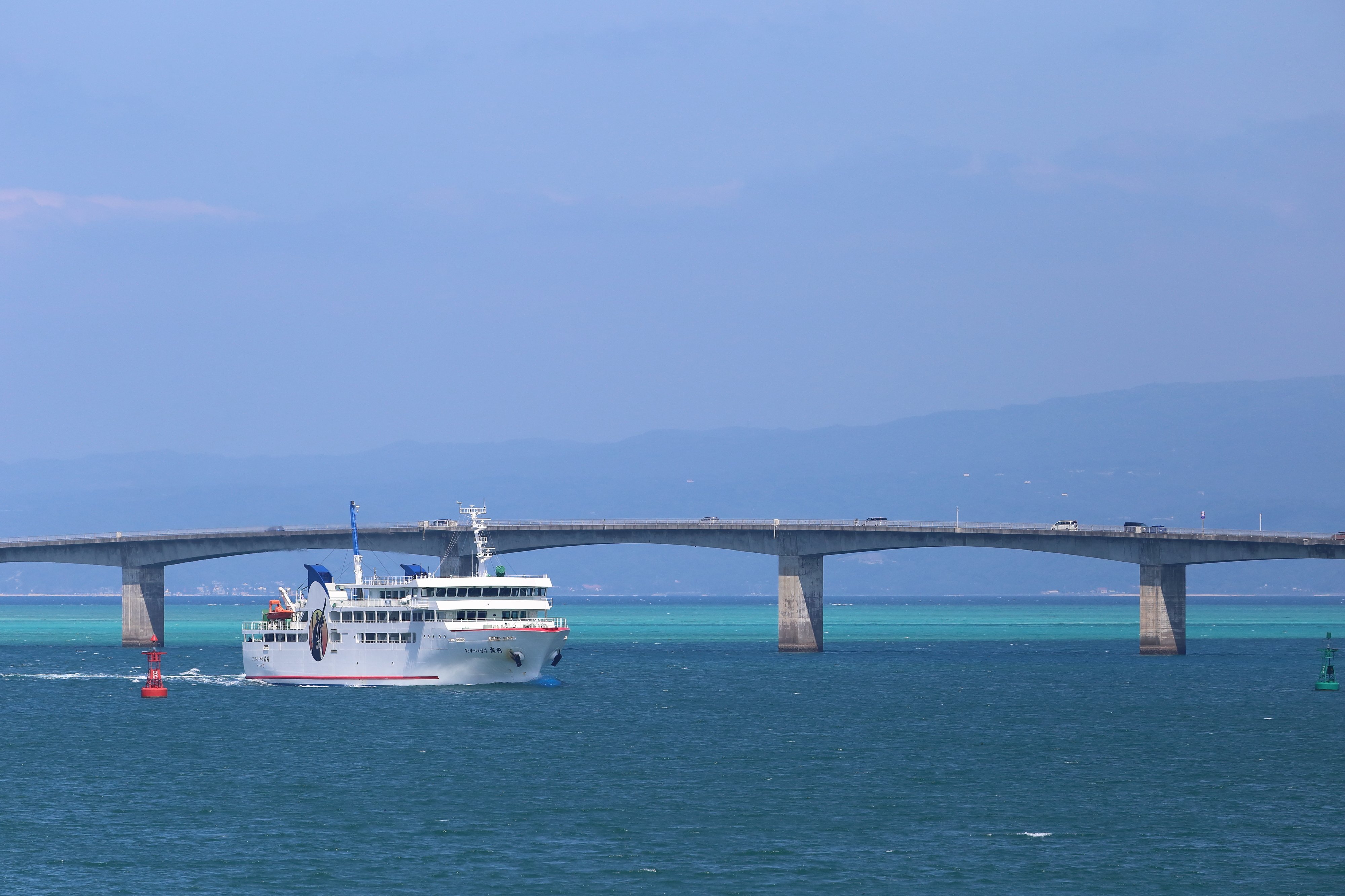 沖縄の海を航行するフェリーいぜな尚円と古宇利大橋